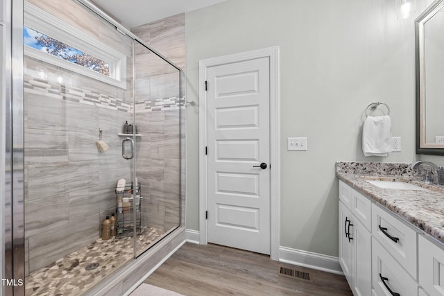 bathroom with hardwood / wood-style floors, vanity, and a shower with shower door