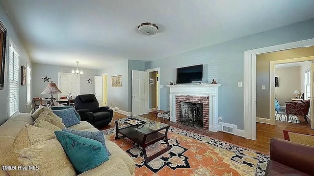 living room featuring a fireplace, hardwood / wood-style floors, and an inviting chandelier