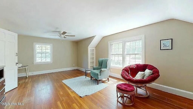 living area with ceiling fan, lofted ceiling, and hardwood / wood-style flooring