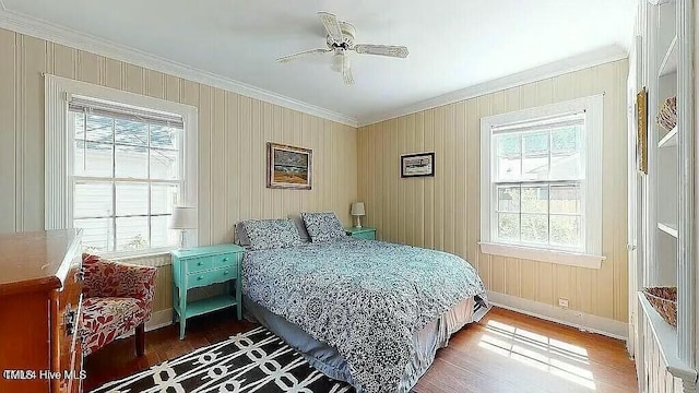 bedroom featuring multiple windows, ceiling fan, crown molding, and wood-type flooring