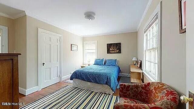 bedroom with hardwood / wood-style flooring and crown molding