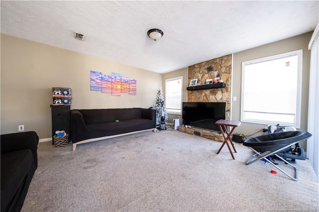 carpeted living room with a wealth of natural light, a fireplace, and a textured ceiling