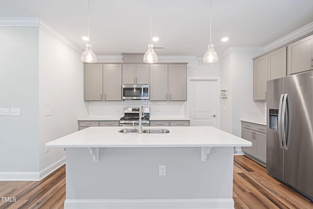 kitchen with a kitchen island with sink, hanging light fixtures, gray cabinets, and appliances with stainless steel finishes