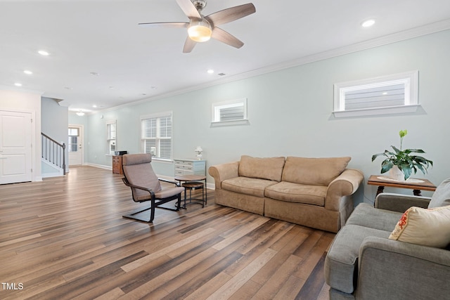 living room featuring hardwood / wood-style flooring, ceiling fan, and crown molding