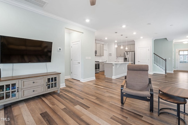 living room with hardwood / wood-style flooring, ornamental molding, sink, and ceiling fan