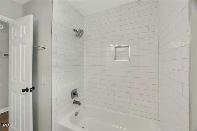 bathroom with wood-type flooring and tiled shower / bath