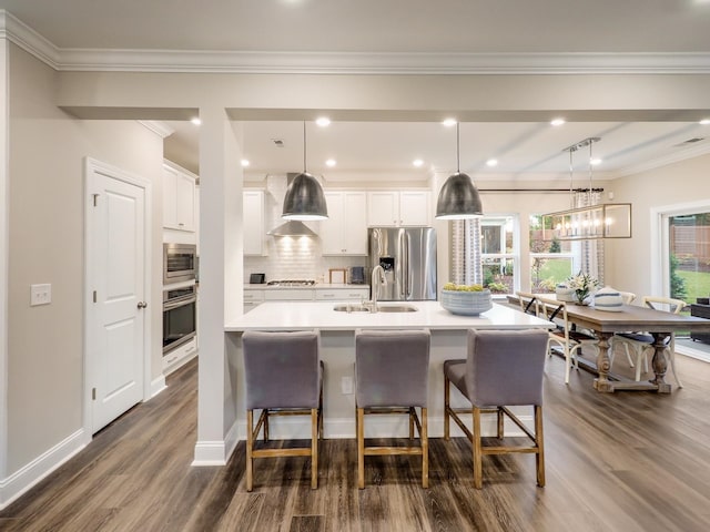 kitchen featuring a kitchen bar, stainless steel appliances, a spacious island, white cabinets, and hanging light fixtures