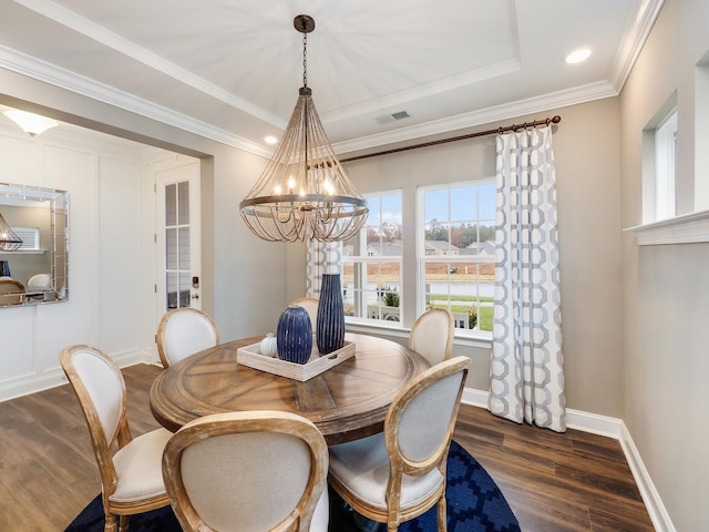 dining room featuring a raised ceiling, dark hardwood / wood-style flooring, an inviting chandelier, and crown molding