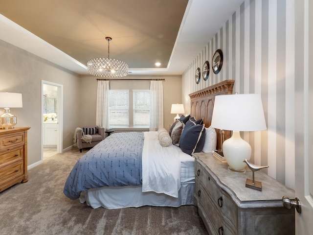 bedroom featuring a raised ceiling, connected bathroom, carpet, and a chandelier