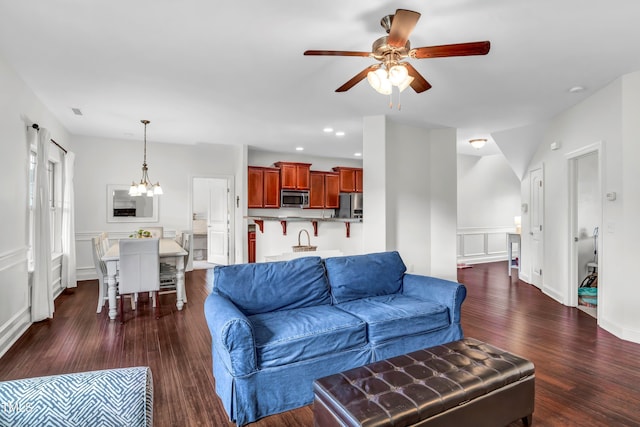 living room with dark wood-type flooring and ceiling fan with notable chandelier