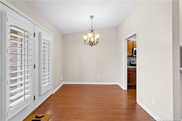 spare room featuring dark hardwood / wood-style floors and a chandelier