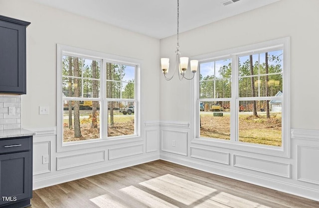 unfurnished dining area with a notable chandelier and wood-type flooring