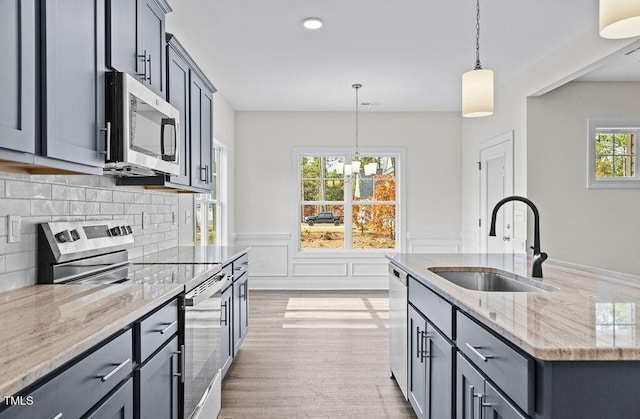 kitchen featuring sink, tasteful backsplash, decorative light fixtures, light stone counters, and stainless steel appliances