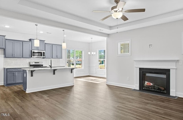 kitchen with decorative backsplash, a kitchen breakfast bar, stainless steel appliances, pendant lighting, and an island with sink