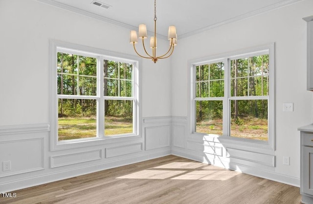 unfurnished dining area with crown molding, light wood-type flooring, and an inviting chandelier