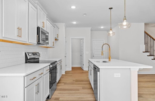 kitchen featuring appliances with stainless steel finishes, tasteful backsplash, a kitchen island with sink, decorative light fixtures, and white cabinets