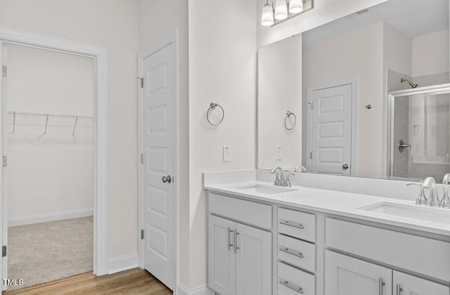 bathroom with hardwood / wood-style floors, vanity, and a shower with shower door