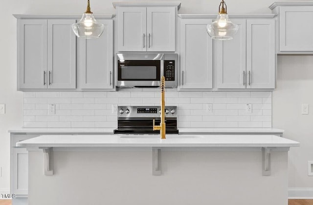 kitchen featuring decorative light fixtures, a kitchen breakfast bar, decorative backsplash, and stainless steel appliances