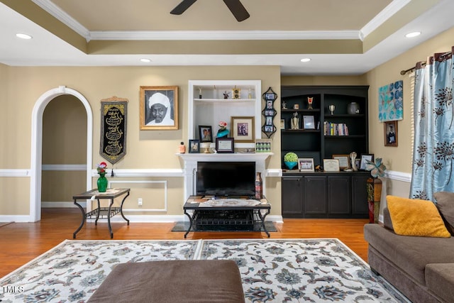 living room with a raised ceiling, ceiling fan, hardwood / wood-style floors, and ornamental molding