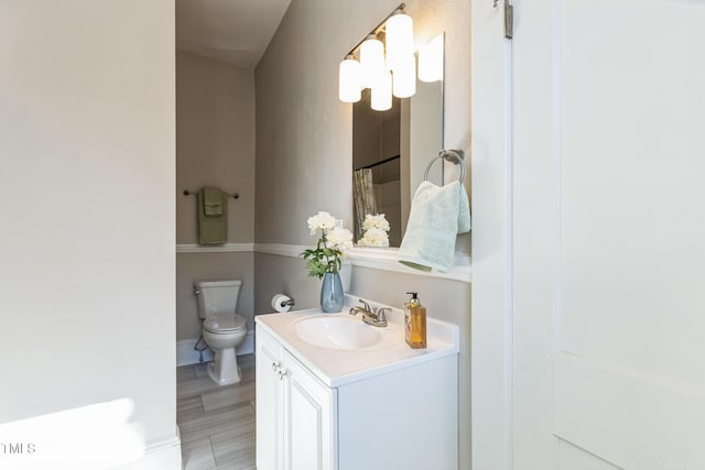 bathroom with wood-type flooring, vanity, and toilet