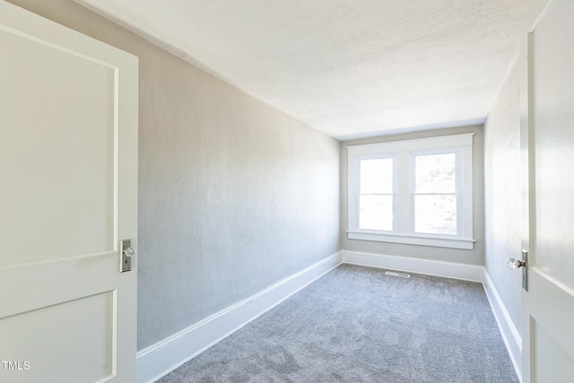 empty room with carpet floors and a textured ceiling