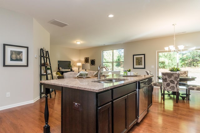 kitchen featuring dishwasher, sink, decorative light fixtures, light stone counters, and dark brown cabinetry