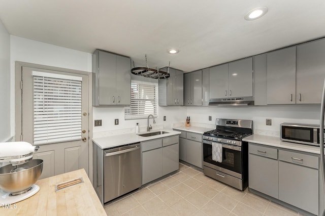 kitchen featuring sink, light tile patterned floors, gray cabinetry, and stainless steel appliances