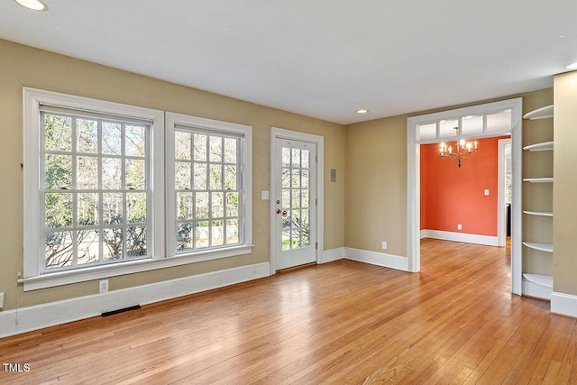 spare room featuring a notable chandelier and light hardwood / wood-style floors