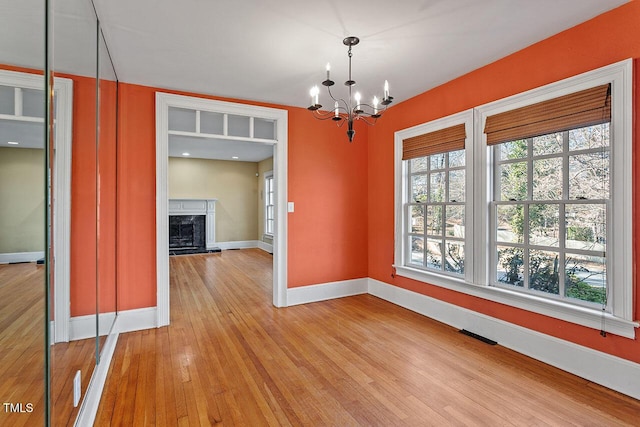 interior space with an inviting chandelier, a high end fireplace, and light wood-type flooring