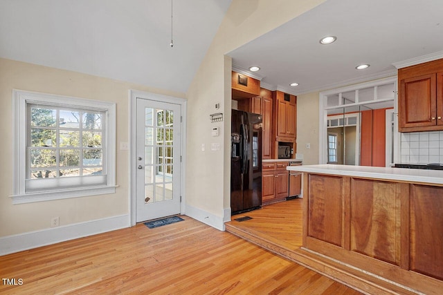 kitchen featuring light hardwood / wood-style floors, decorative backsplash, and black appliances