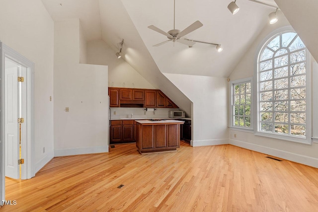 kitchen featuring a kitchen island, high vaulted ceiling, light hardwood / wood-style flooring, and rail lighting