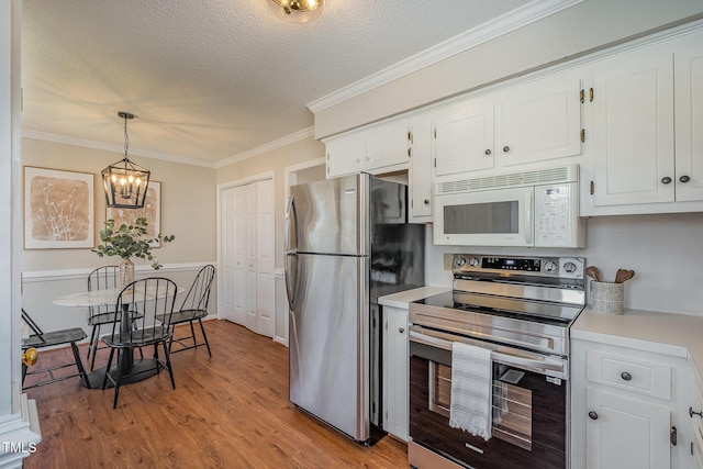 kitchen featuring stainless steel appliances, hanging light fixtures, crown molding, a textured ceiling, and white cabinetry