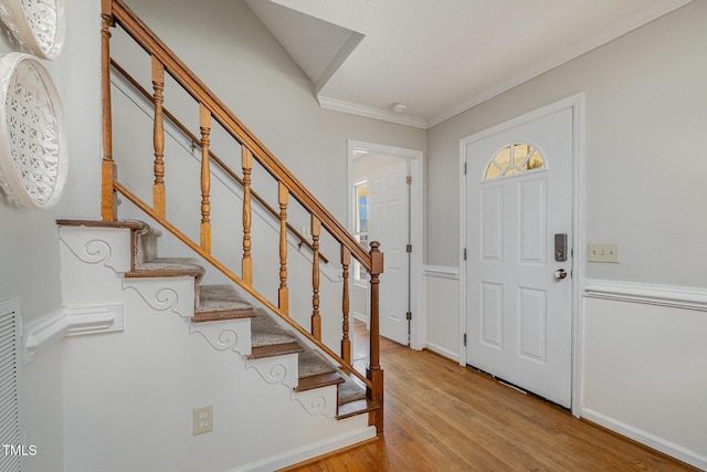 foyer entrance with ornamental molding and light hardwood / wood-style flooring