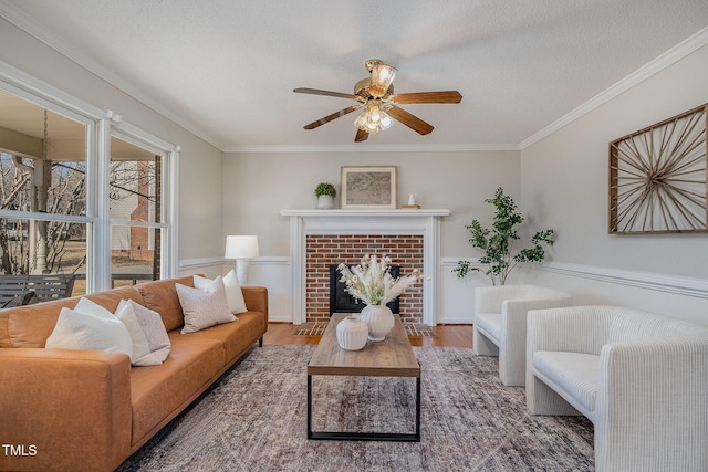 living room featuring a textured ceiling, ceiling fan, a brick fireplace, crown molding, and dark wood-type flooring