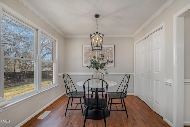 dining area featuring a notable chandelier, dark hardwood / wood-style flooring, and crown molding