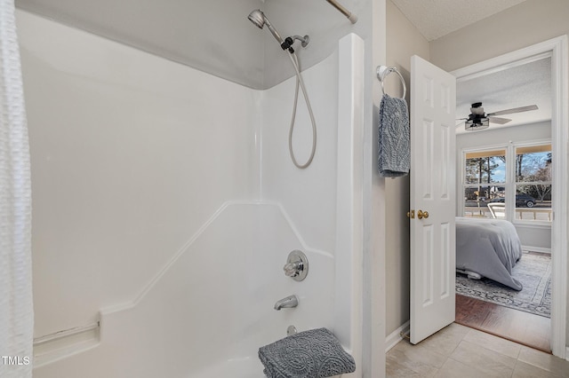 bathroom with ceiling fan, shower / washtub combination, a textured ceiling, and tile patterned floors