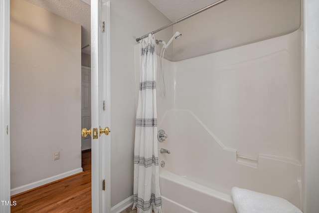 bathroom featuring a textured ceiling, wood-type flooring, and shower / tub combo with curtain