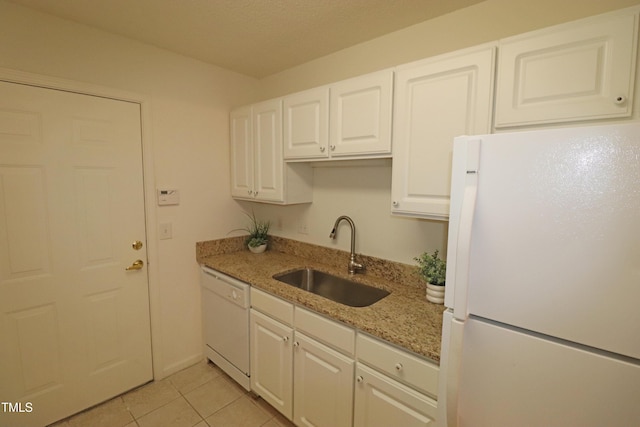 kitchen with light stone countertops, white appliances, sink, light tile patterned floors, and white cabinetry