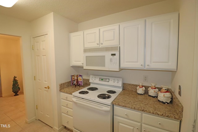 kitchen with white cabinets, light stone counters, a textured ceiling, white appliances, and light tile patterned floors