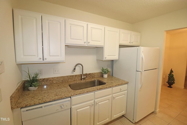 kitchen featuring white appliances, white cabinets, sink, light tile patterned floors, and light stone counters