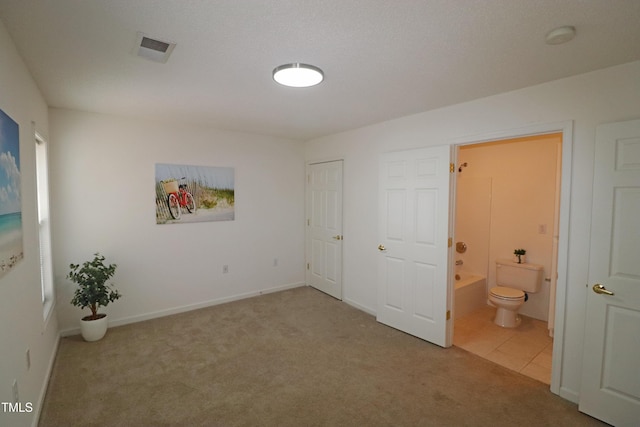 unfurnished bedroom featuring ensuite bathroom and carpet floors