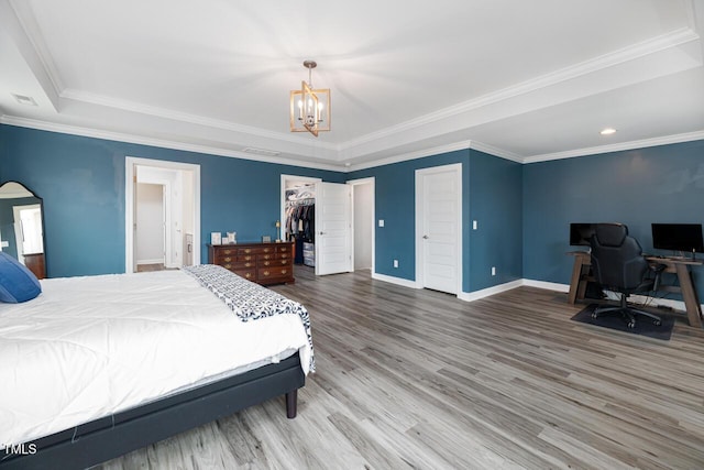 bedroom with a walk in closet, crown molding, a closet, and a chandelier