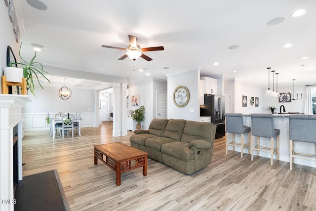 living room with light wood-type flooring, ceiling fan, and crown molding