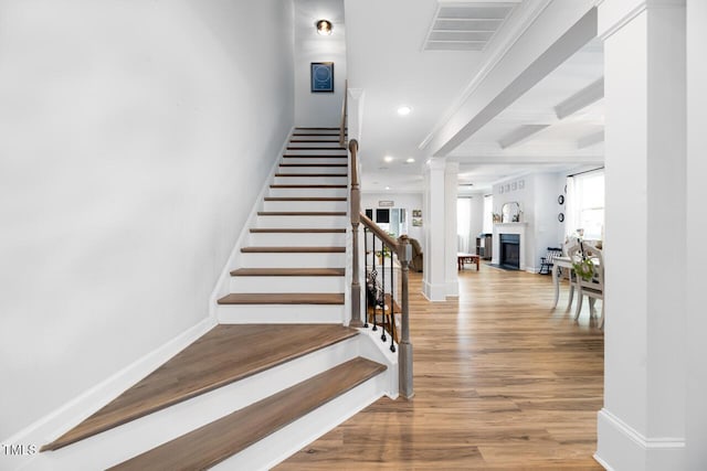 stairs with hardwood / wood-style floors, crown molding, and beam ceiling