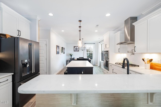 kitchen with a center island, backsplash, wall chimney range hood, appliances with stainless steel finishes, and white cabinetry