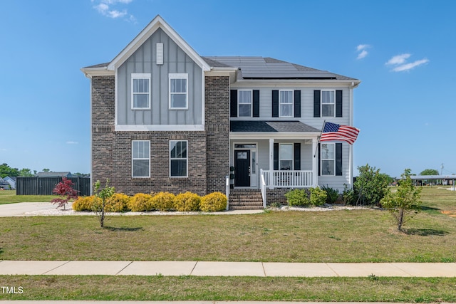 147 E Wellesley Dr, Clayton, NC 27520 - view of front of house featuring a front lawn, covered porch, brick siding, board and batten siding, and roof mounted solar panels