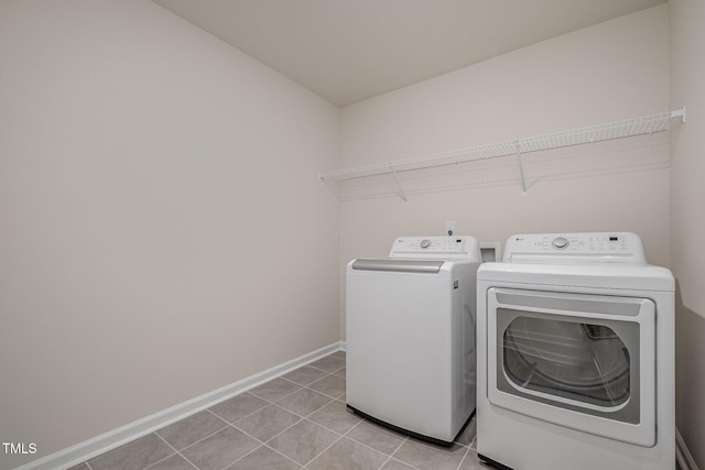 clothes washing area featuring washer and clothes dryer and light tile patterned floors