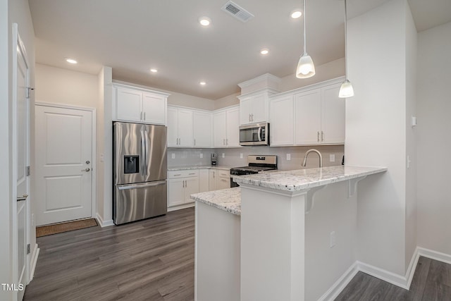 kitchen with decorative light fixtures, kitchen peninsula, decorative backsplash, white cabinetry, and appliances with stainless steel finishes