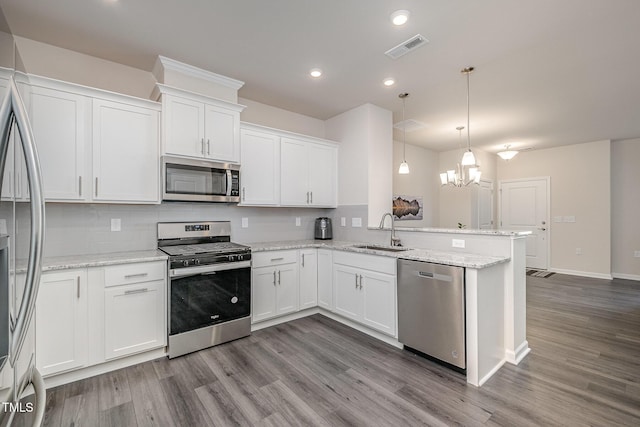 kitchen with pendant lighting, kitchen peninsula, sink, stainless steel appliances, and white cabinets