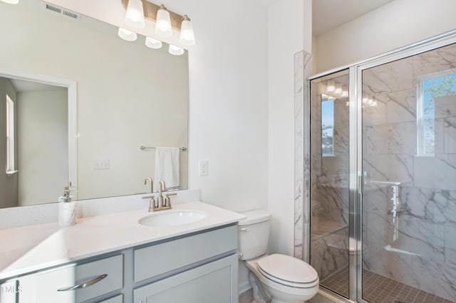 bathroom featuring vanity, toilet, and a shower with shower door